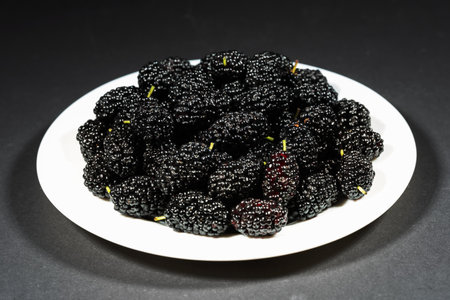 Sweet berries of black mulberry on the plate.の写真素材
