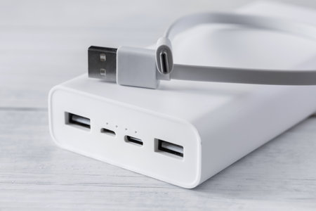 white power bank for charging smartphones and various digital devices on a white wooden background.の写真素材