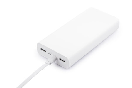 Powerbank for charging mobile devices with cable on white table.の写真素材