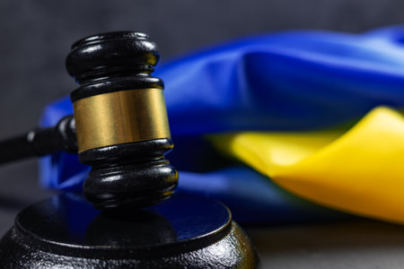 Judge gavel and flag of Ukraine on dark background. Blue yellow Ukrainian flag and wooden judge gavel. Concept Ukrainian trial, law, authority. Conflict and war in Ukraine.の写真素材