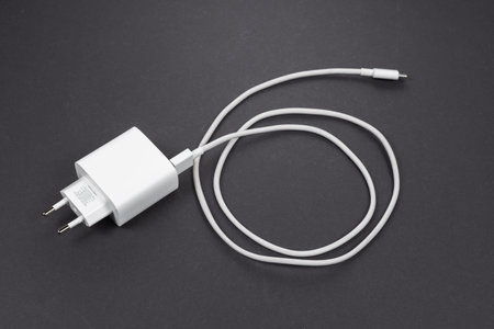 White smartphone charger and USB cable on dark background.