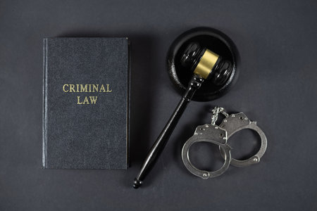 Law book, judge's gavel and handcuffs on gray textured table.の写真素材