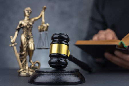 Judge with paper document pronouncing sentence in a court of law. Judge finds the accused guilty, passes judgment and rules case closed. Hand holding gavel and hitting sound block in close-upの写真素材