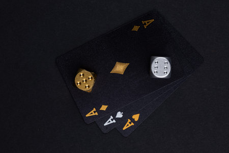 three aces cards and two dice on a dark background.