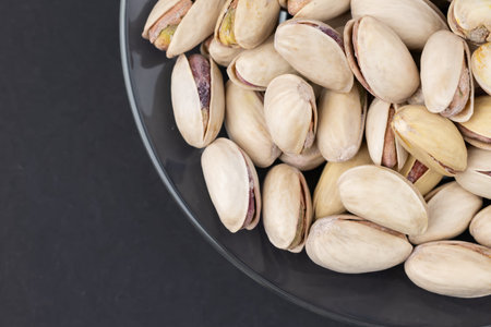 Salted Pistachios for Beer, Macro, on black Background of a Beer Snack of Salted Pistachio Nuts....