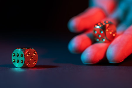 Hand throws dice on a dark background with selective focus.