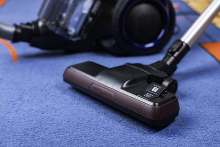 Modern vacuum cleaner with brush on carpet in room.