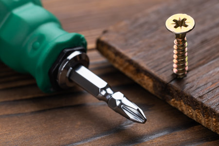 screwdriver and screws on wooden background close up.