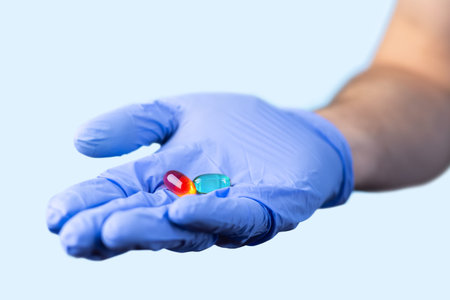 medical worker or pharmacist hands wearing blue latex protective gloves, hold red and green medicine...