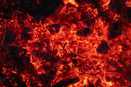 background of burning and glowing hot coals. smoldering embers of fire. flicker of burning coals at...
