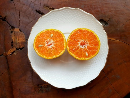 Closeup top view, the white plate of a slice of oranges on wooden background.の素材