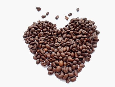 Closeup top view pile of coffee beans in heart shape background, selective focus.