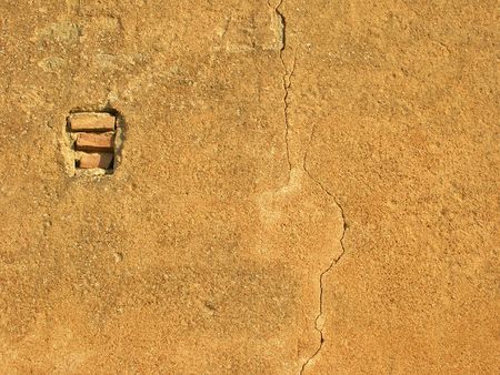 A stucco crackled wall with visible bricksの写真素材