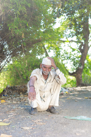 Maharashtra , India - April 2023 Indian old farmer, loss in farm , Old Indian men sitting tired,...