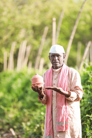 Indian farming happy farmer holding piggy bank in farm, poor farmer, farmer savingの写真素材