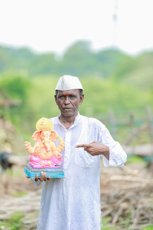 Indian old man holding Lord Ganesha idol in hands , happy old poor manの写真素材