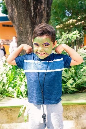 Vertical photo of a Latin boy with his face painted showin his muscles