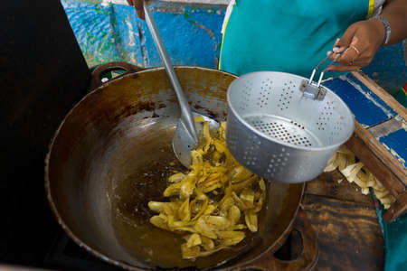 A Latin woman tends her retail business on the street and cooks fried sliced plantainsの写真素材