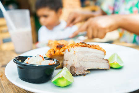Close-up of a large piece of chicharron while a woman cuts meat to feed her sonの写真素材
