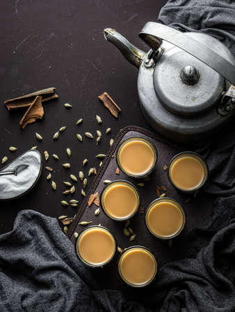 Indian chai in glass cups with metal kettle and other masalas to make the tea.の写真素材