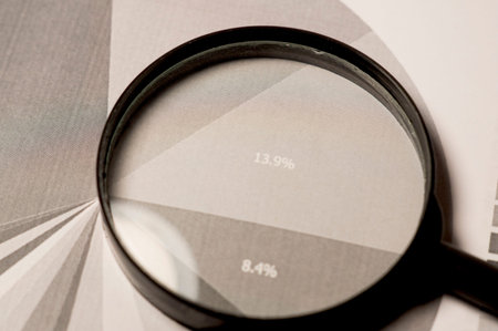 Magnifier lies on the financial charts in the office. Black and white background.