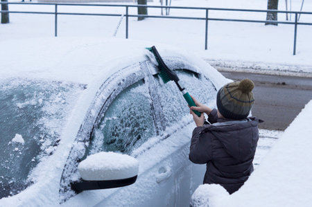 little boy cleans snow from carの写真素材