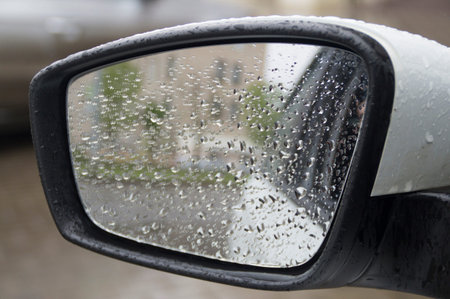 a side mirror of a modern car in raindrops