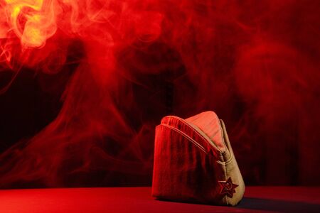 An old Soviet military cap of khaki on a black background with red light and smoke.の写真素材