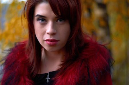 portrait of a girl with red hair in the autumn forestの写真素材