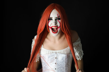a girl in a clown costume with scary makeup on a black background