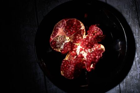 garnet on a black plate on a black background in a low keyの写真素材
