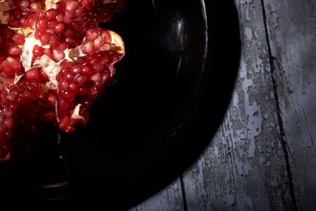 garnet on a black plate on a black background in a low keyの写真素材