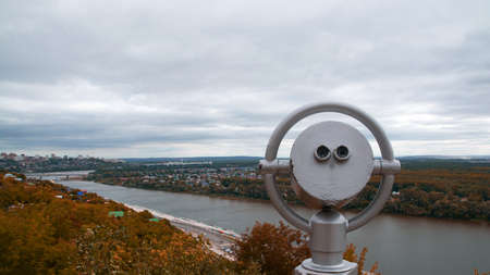 binoculars on the observation deck.mountain view of the city and autumn forestの写真素材