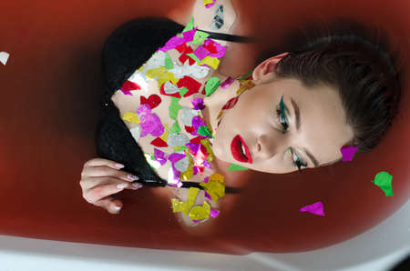 girl with bright makeup in a bath with red water.の写真素材