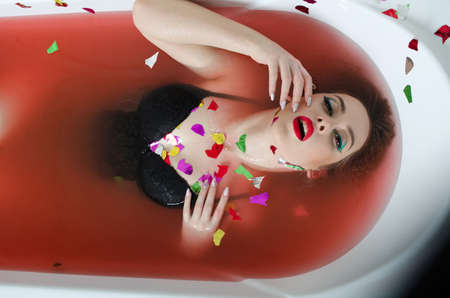 girl with bright makeup in a bath with red water.の写真素材