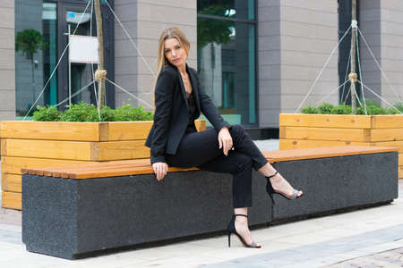 a blonde woman in a black business suit in the city.businesswoman on a walkの写真素材