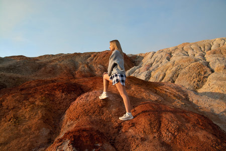 a young blonde girl in casual clothes in the mountains of red clay.ural mars. quarry for the extraction of refractory clay.の写真素材