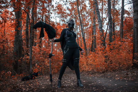 a girl in a bdsm costume and a black mask in a red forest.an idea for halloween