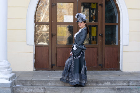 a woman dressed as a 19th century noblewoman stands near an old manor house.russian winter.の写真素材