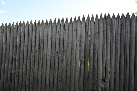 an old gray wooden fence made of logs with sharp ends