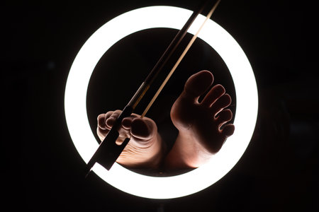 female legs with a violin bow in close-up in a round lamp. the concept of playing the violinの写真素材