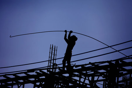 Construction worker is working on steel roof , silhouette , blue sky