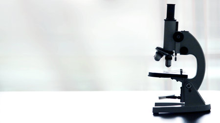 Microscope on white table on white background with copyspace , close up