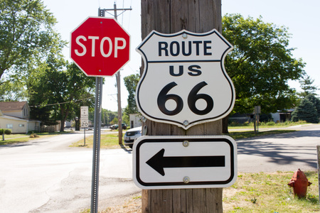 Route 66 Sign with Left Pointing Arrow and Stop Sign in the background.の写真素材