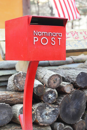 Red postbox with a pile of wood.の写真素材