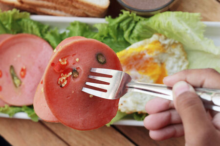 Ham cut into circular discs with red peppers and egg fried の写真素材