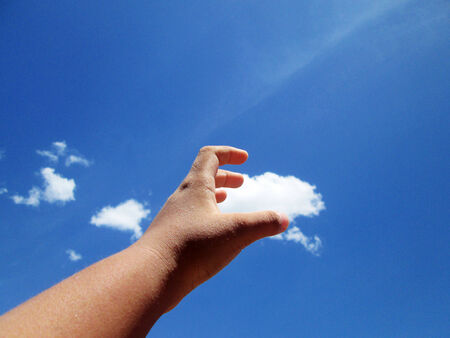 Hand and clouds on the blue sky.の写真素材