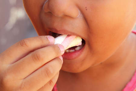 Child eating a marshmallow pink.の写真素材