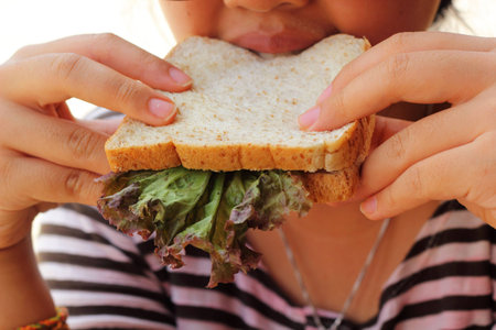 Ladies eating a tuna sandwich with gusto.