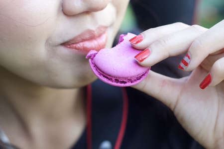 Woman eating french deliciously macaroonsの写真素材